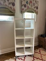 Front view of white Kallax shelf unit with 8 square compartments, two columns by four rows, on wheels.