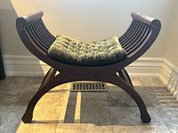 Front view of wooden Roman style bench with green velvet tufted cushion, showing curved sides and legs.