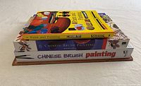 Stack of 5 items including art books and Chinese brush painting kits, viewed from top
