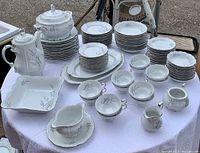 Full view of china set showing cups, saucers, bowls, serving bowls, platters, coffee pot, creamer, sugar bowl, and plates.