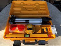 Overview photo inside original yellow case showing tripod, red goggles, circular level, small attachments, and spirit level.