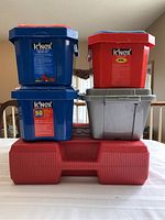 Stacked K'NEX storage tubs including blue, red, gray tubs, and large red hard-side case