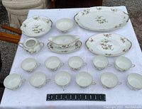 Full lot overview showing three serving platters, 11 teacups, sauceboat, and sugar bowl on white cloth.