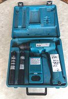 Makita 6095D power drill, two batteries, and fast charger inside blue carrying case.