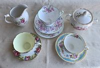 First photo showing all pieces from above on a cloth background with visible floral patterns and gold trims.