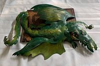 Green metal dragon cut-out wall hanging showing front side details with wings, head, tail, and claws