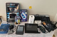 Full lot overview showing all electronic items including packaged car kit, UV sanitizer, Kindle, keyboards, microphones, and digital wireless monitor.