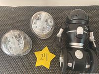 Two transparent Sphero Bolt robot balls with sensors and clear cases alongside one WowWee MiP black and silver robot on a grey surface.