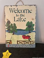 Front view of the 11x14 slate stone plaque with a lakeside scene, dock, red boat, trees, water, and text "Welcome to the Lake". Shows stone texture and rope hanger.