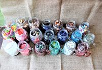 Overview of all twenty glass mason jars lined up in rows, showing varied colored contents and jar designs with handles and metal lids.