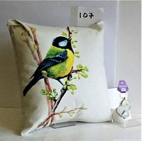 Square fabric item with a printed bird illustration sitting on a twig.