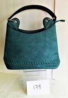 Front view of teal handbag showing shape, handle, and decorative stitching at bottom edge.