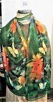 Front view of the scarf displayed on a mannequin showing vibrant flowers and butterflies with a green background.
