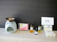 Ceramic diffuser container, three bottles of scented oils, and three packages of scented wax cubes arranged on a table.