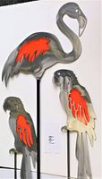 Three metal red and silver/steel garden stakes featuring one flamingo and two parrots against a white background.