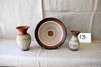 Lot showing plate centered with two vases flanking sides on cloth backdrop