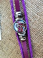 Close-up photo of bracelet showing circular art centerpiece and braided purple leather strap.