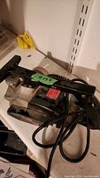 Photo showing black Craftsman electric planer with handle and power cord, placed on shelf.