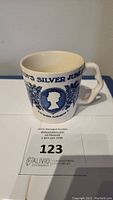 Side view of ceramic collectible cup with blue decorations and text about Queen Elizabeth II's Silver Jubilee