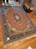 Photo of a rectangular decorative area rug with floral and central medallion pattern placed on hardwood floor, showing overall condition and pattern details.