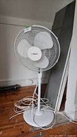 Full view of the white Hawaiian Breeze stand up fan showing the base, pole, and fan head with protective grille and blades.