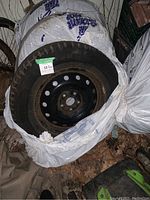 Tire and rim viewed from the side, showing tire on steel rim with some dirt and rust on rim.