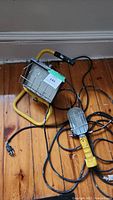 Large and handheld Trebble work lamps on wooden floor showing cords, frames, and wire guards.