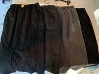 Five grey skirts arranged flat showing variety of grey shades and textures including pinstripe and knit