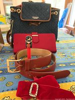 Full view of all items including Guess purse, red clutch, velvet ribbon, belts, and Pez dispenser on a patterned tablecloth.
