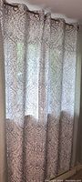 Gray floral patterned semi-sheer curtain panels hung on rod