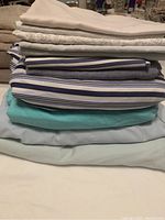 Stack of various folded sheets and duvet covers including striped and solid colors.