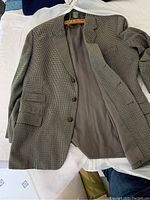 Bespoke Saville Row fine wool houndstooth jacket with leather buttons and inner lining shown open on a flat surface
