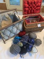 Collection of assorted yarn balls including thick grey, maroon, black, blue, variegated and merino wool and fabric knitting holder and lined wicker sewing box.