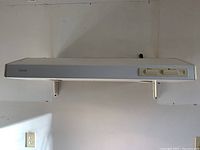 White NuTone slim range hood mounted on wall, showing full profile including mounting brackets and control panel.