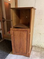 Front view of the solid pine storage unit showing the open upper compartment and closed lower compartment with door and knob.