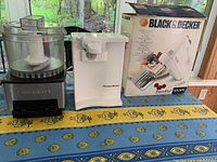 Photo showing Cuisinart food processor, Kitchen Works electric can opener, and boxed Black & Decker handheld mixer on a table