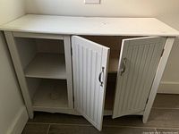 Front view of lower cabinet with two doors open showing interior shelving and visible scratches on surface