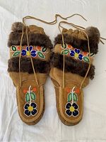 Full view of pair of tan suede mukluks with floral beadwork and brown fur trim, showing overall condition and laces.
