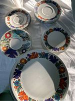 Top view showing various plates and saucers with colorful bird and flower designs in the Villeroy & Boch Acapulco pattern.