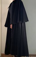 Side view of the vintage long black wool cape worn by a mannequin, showing full length and drape.
