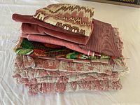 Stack of various folded vintage fabric pieces showing red quilted fabric and patterned pieces