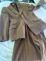 Photo of a houndstooth tweed blazer with structured sleeves paired with a brown corduroy skirt.