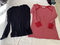 Photo of two long sleeve shirts laid out flat: navy J.Crew cotton shirt and red/white striped Carve cotton blend shirt