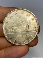 Front side of the 1962 Canadian silver dollar coin showing two men in a canoe with the text 'CANADA DOLLAR 1962'.