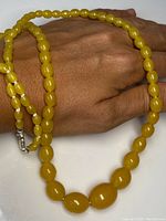 Necklace held in hand to show bead size and clasp detail