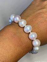 Close-up view of chunky white pearls on wrist, showing size and natural pearl irregularities.