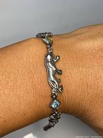 Bracelet worn on wrist showing silver cougar links and green rectangular gemstone accent.
