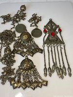 Photo showing the full collection of three antique Middle-Eastern silver jewelry pieces on a white surface for detail capture