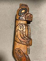 Front view of entire carved rattle showing standing figure and handle