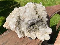 Top and angled close-up view of the quartz geode showing the crystal formations, pyrite clusters, and metal bear figure.